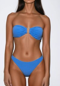 Blauwe bandeau bikini met geplooid stof, met een gouden accent in het midden. De onderkant heeft een low-rise ontwerp, in dezelfde kleur en textuur.