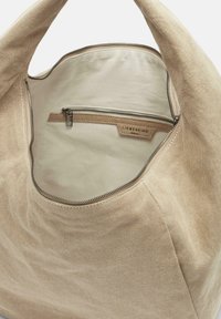 Beżowa torebka z płótna, z zamknięciem na zamek błyskawiczny i wewnętrzną kieszenią ze srebrnym zamkiem. Wnętrze jest jasnobeżowe o gładkiej fakturze.