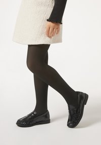 Schwarze Leder-Mokassins mit glänzender Oberfläche, die mit einem fransigen Detail an der Zehenpartie und einem niedrigen, stabilen Absatz ausgestattet sind.