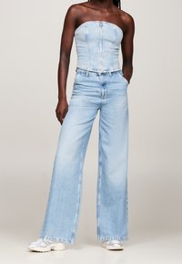 Ljusblå denim tvådelad outfit med ett axellöst, figurnära top med dragkedja framtill och vida jeans med hög midja.