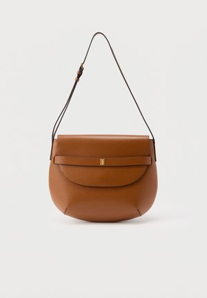 Brown leather shoulder bag with curved flap and adjustable strap, featuring a small gold emblem on the front strap detail.