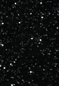 Gros plan d'un tissu noir densément recouvert de petits sequins noirs brillants reflétant la lumière de manière inégale.