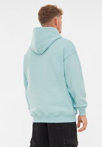 Felpa con cappuccio di colore azzurro chiaro, con maniche lunghe, polsini a costine e una vestibilità comoda. Texture morbida e design semplice senza loghi o fantasie.