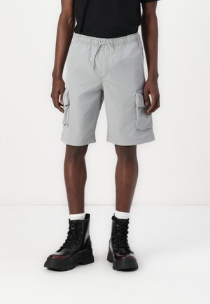 Gray cargo shorts with an elastic waistband and drawstring, featuring two side pockets and a smooth texture. Worn with black combat boots.