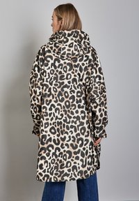 Abrigo impermeable con estampado de leopardo, con capucha amplia, mangas largas y un corte relajado. Presenta una textura brillante y suave, además de aberturas laterales.