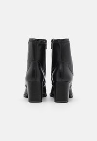 Black leather ankle boots with a smooth finish, high block heels, and zip closures at the back. Features decorative stitching along seams.