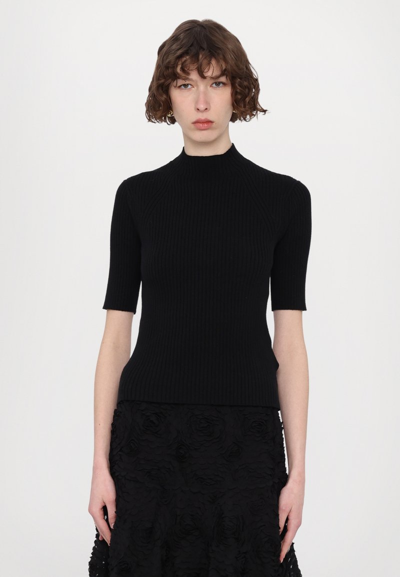 Top nero a coste con maniche corte, scollo alto e silhouette aderente, abbinato a una gonna floreale nera con texture.