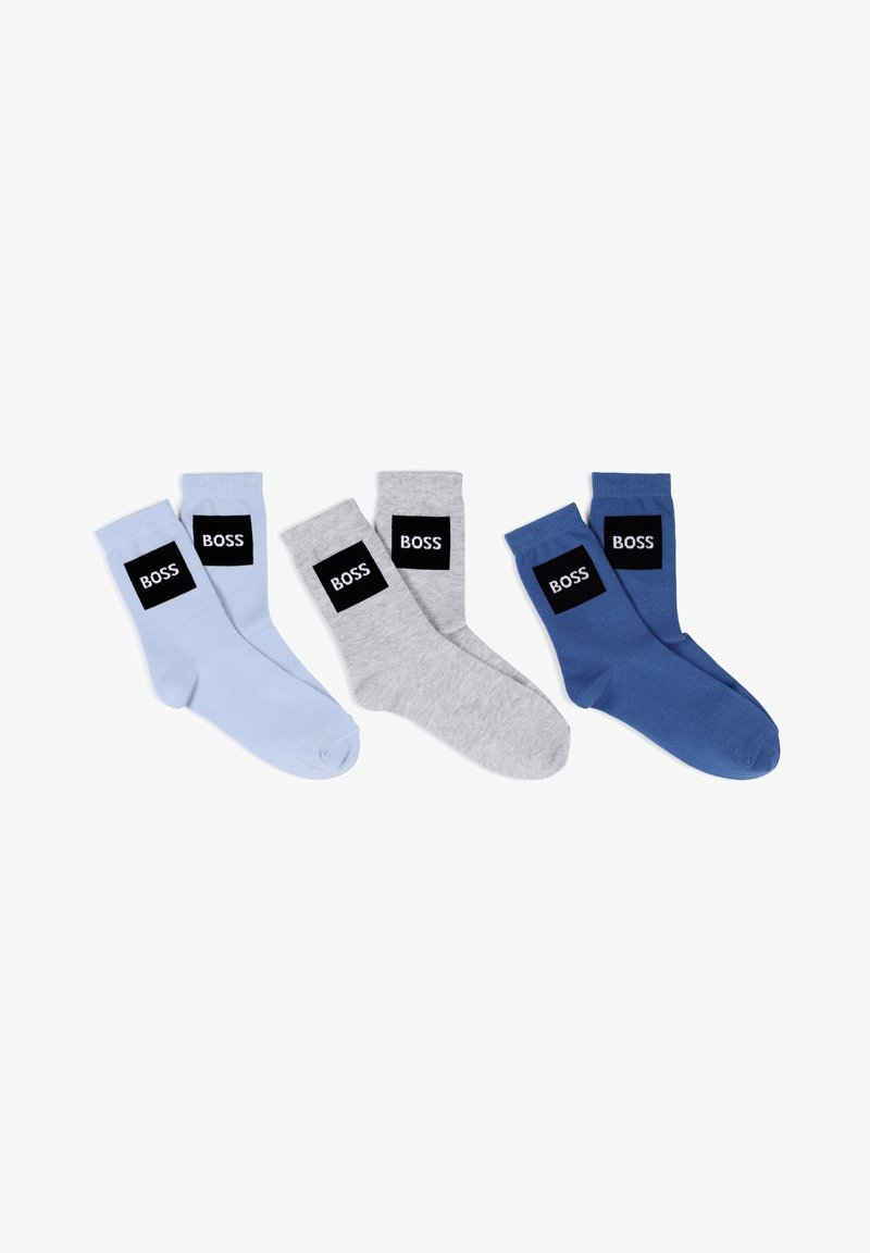Quatre paires de chaussettes en bleu clair, gris et bleu marine. Chacune comporte une étiquette rectangulaire noire avec le texte "BOSS" en blanc. Matière en coton.