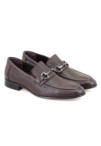 Bruine leren loafers met een gestructureerde afwerking, voorzien van een zilveren gespaccent en een lage hak. Het ontwerp bevat decoratieve stiksels.