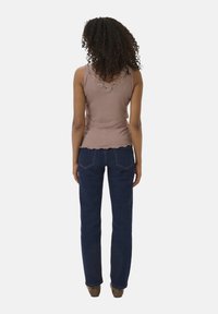 Débardeur marron avec dentelle, associé à un jean droit bleu foncé. Texture côtelée sur le haut et tissu en denim lisse.