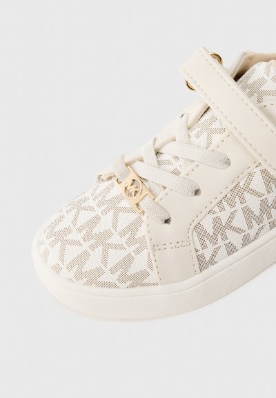 Λευκό αθλητικό παπούτσι με σχέδιο πλέγματος και γεωμετρικό μοτίβο, δερμάτινες λεπτομέρειες, χρυσά αξεσουάρ και ιμάντα με αγκράφα για ασφαλή εφαρμογή.