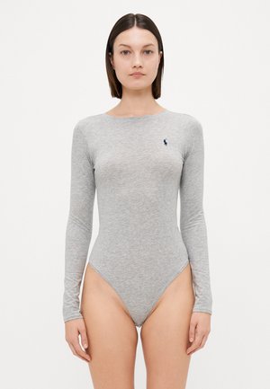 Svetlo siva bodysuit z dolgimi rokavi, izdelan iz mehkega materiala, z okroglim izrezom in majhnim mornarsko modrim logotipom na levem prsnem delu. Visoko izrezane noge.