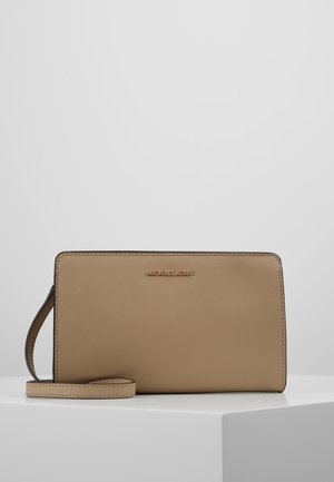 Prostokątny brązowy portfel na nadgarstek z złotym logo „Michael Kors” i odpinanym paskiem, prezentowany na białej powierzchni na jednolitym tle.