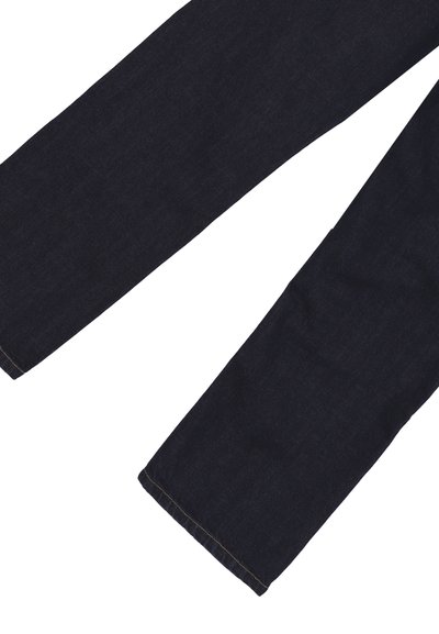 Gambe di pantaloni in denim blu scuro con visibile cucitura marrone lungo gli orli, distesi su uno sfondo bianco.