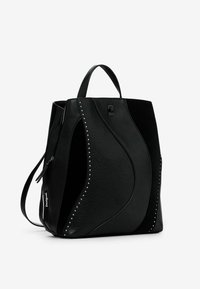 Schwarzer Leder-Rucksack mit strukturierter Oberfläche, geschwungenem Design und genoppten Akzenten. Mit Tragegriff oben und verstellbarem seitlichen Riemen.