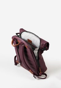 Zaino a forma di cilindro in color bordeaux con accenti in pelle beige, fodera interna grigia, chiusura con zip e spallacci regolabili, mostrante una vista dall'alto aperta.