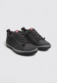 Zapatillas negras con un upper liso, cordones texturizados y detalles en gris. Presenta una suela acolchada y una etiqueta en la parte trasera para tirar.