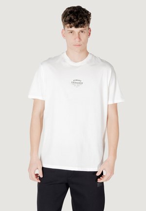 T-shirt bianco in cotone con collo rotondo e maniche corte, con un piccolo logo nero "Armani Exchange" sul petto.