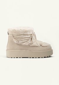 Beige suede ankle boots with faux fur lining, flat rubber sole, and a lace-up design. Textured accents and a padded collar detail.