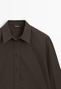 Dunkelbraunes, knöpfbares Hemd mit spread Kragen, aus glattem Stoff. Verfügt über sechs Knöpfe und ein Markenlabel auf der Innenseite.