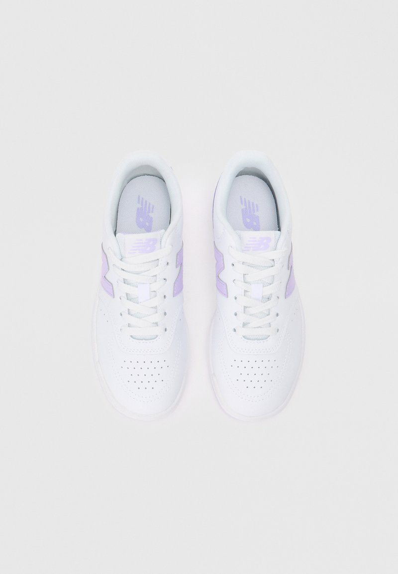 Baskets blanches avec des accents violets, fabriquées en matériau synthétique. Les caractéristiques incluent des détails perforés, un design à lacets et un col rembourré.