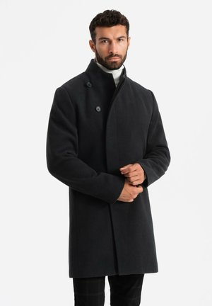 Cappotto di lana nera con colletto alto e chiusura a doppio petto, caratterizzato da una texture liscia e una vestibilità sartoriale.