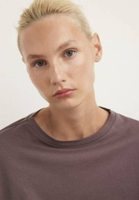Maglietta a maniche corte con scollo tondo in mauve smorzato. Tessuto morbido, vestibilità comoda e design minimalista senza motivi o decorazioni visibili.