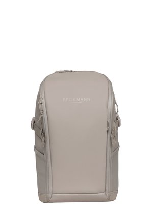Beige rektangulær Beckmann-ryggsekk med flere glidelåslommer og sidelommer, designet for daglig bruk og reise.
