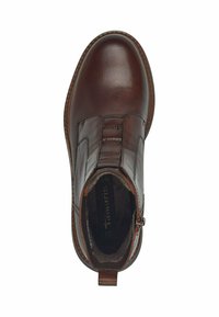 Bota de tobillo de cuero marrón con acabado suave, paneles laterales elásticos, un zipper decorativo y un tirador en el talón.