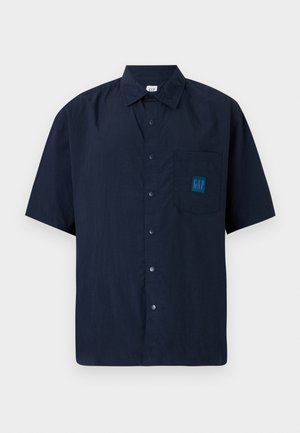 Navy blue short-sleeve button-up shirt made from lightweight fabric, featuring a chest pocket with a GAP logo patch in teal.