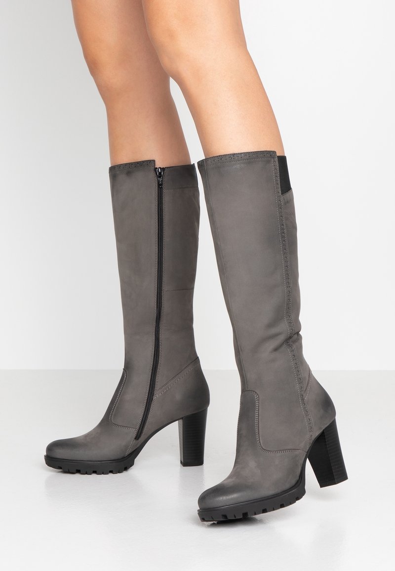 Bottes grises hauteur genou en cuir lisse, avec une fermeture éclair à l'avant, un talon épais et une semelle en caoutchouc avec un motif de bande de roulement texturé.