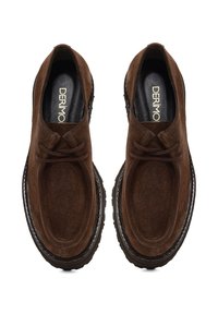 Braune Wildlederschuhe mit Mokassin-Design, ausgestattet mit einer runden Spitze und Schnürung. Die Sohle ist aus schwarzem Gummi mit strukturierter Oberfläche.