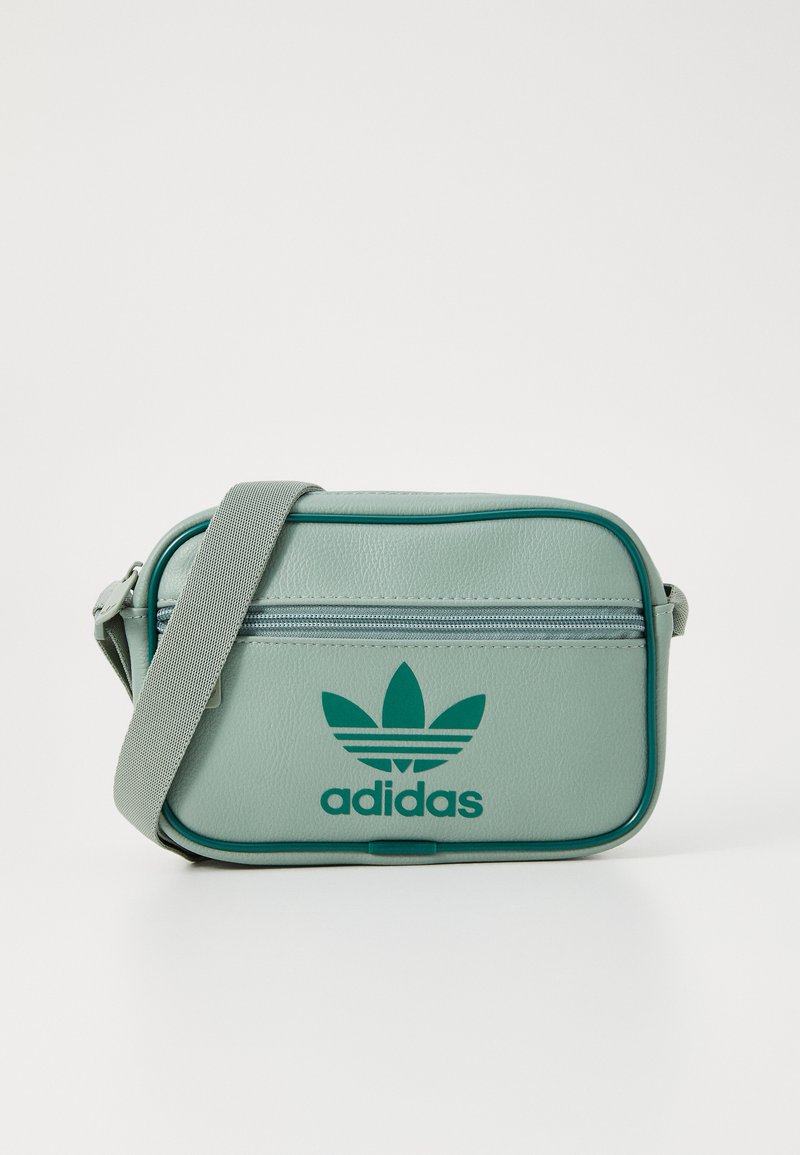 Zelená syntetická kožená crossbody taška se zipem, s vyraženým logem Adidas a kontrastním tmavě zeleným lemem.