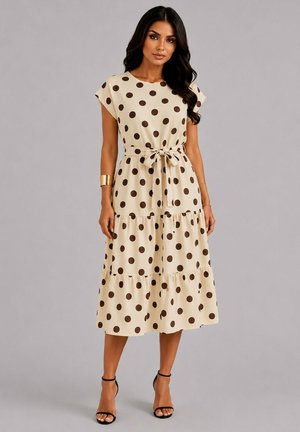 Femme portant une robe midi beige à pois marron, une ceinture nouée à la taille, des manches courtes et des sandales noires à talons hauts.