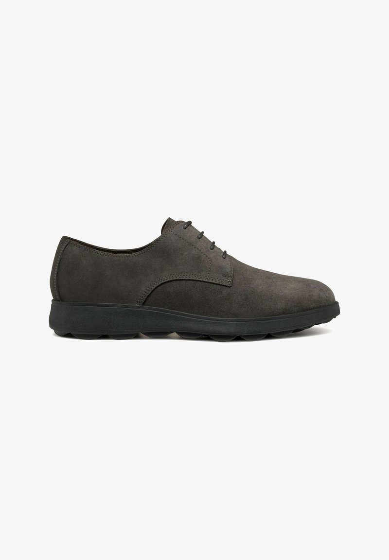 Chaussure de ville pour homme à lacets en daim gris foncé avec semelle en caoutchouc noire, talon bas et bout arrondi, vue de profil.