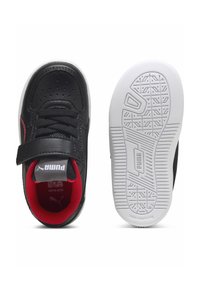 Zapatillas de cuero negro con acentos rojos, correa de velcro y puntera perforada. Suela de goma blanca con patrones de agarre texturizados.