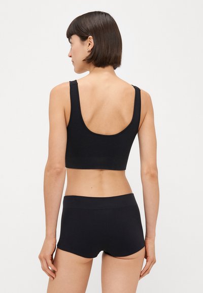 Črn rebrast športni crop top in ujemajoče se kratke hlače, ki imajo široko izrezano ovratnik, debele naramnice in gladek, elastičen pas.