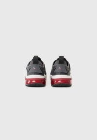 Des chaussures de sport grises avec des accents rouges, présentant une tige en maille, un col rembourré et une semelle texturée. Design à enfiler avec une languette.