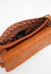 Taske i tanfarvet læder med præget geometrisk mønster, gyldent beslag og foer med blomsterprint. Indeholder en indvendig lynlåslomme.