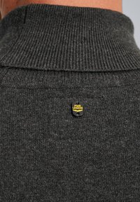 Grauer Pullover-Strickpullover mit hohem Rippenkragen, der ein kleines schwarzes und gelbes PME Legend-Logoetikett nahe dem Hals aufweist. Strukturierter Stoff.