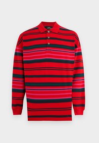 Μανίκι μακρύ κόκκινο πόλο πουκάμισο με οριζόντιες μαύρες, πράσινες και ροζ ρίγες και τρία κουμπιά στον γιακά.