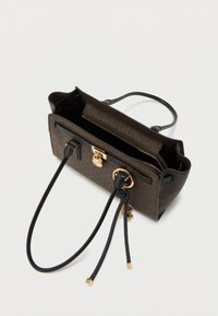 Καφέ τσάντα με σχέδια, μαύρες δερμάτινες λεπτομέρειες, χρυσά μεταλλικά στοιχεία και εσωτερική τσέπη με φερμουάρ. Διαθέτει μακριές μαύρες λαβές και διακοσμητικά γούρια.