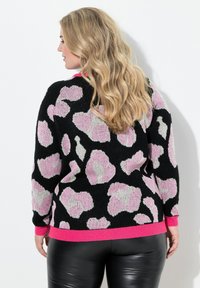 Schwarzer Pullover mit großen rosa und grauen Blumenmustern, geripptem rosa Saum und Bündchen, langen Ärmeln und einem weichen, strukturierten Strick.