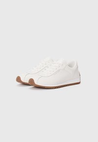 White leather sneakers with a smooth finish, featuring a textured brown rubber sole and subtle gray accents on the side.