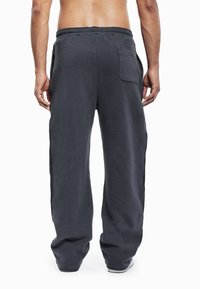 Donkergrijze joggingbroek met een comfortabele pasvorm, elastische tailleband en een achterzak met klep, gemaakt van een zachte, gestructureerde stof.