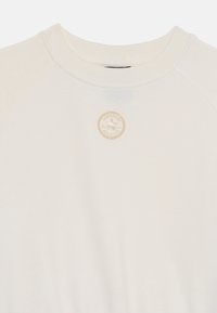 Kremfarvet sweatshirt med rund halsudskæring, raglanærmer og et stofmærke med logo på brystet. Blød tekstur, afslappet design.