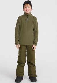 Pull-over en polaire vert olive avec un zip demi-long et des manches longues, associé à un pantalon décontracté assorti en vert olive et des bottes noires.