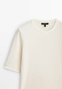 Valkoinen pyöreäkauluksinen t-paita, joka on valmistettu pehmeästä puuvillasta. Siinä on lyhyet hihat, sileä pinta ja minimalistinen muotoilu, joka sopii erinomaisesti rentoon pukeutumiseen.