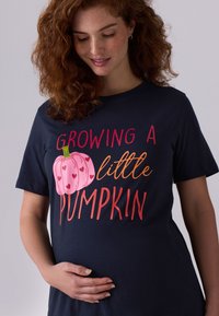 Merevköie puuvillane t-särk, millel on mänguline roosa kõrvitsa graafika koos südametega, tekstiga "Kasvatan väikest kõrvitsat" soojades toonides, lühikeste varrukatega, lõdvestunud lõikega.