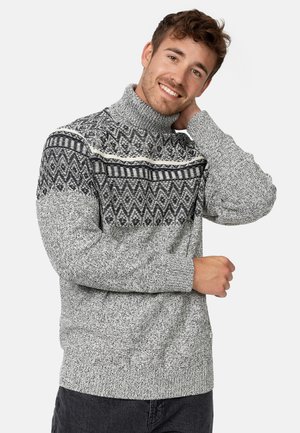 Suéter de punto gris con un cuello alto y un patrón geométrico en blanco y negro en el pecho. Tela texturizada con puños de canalé.